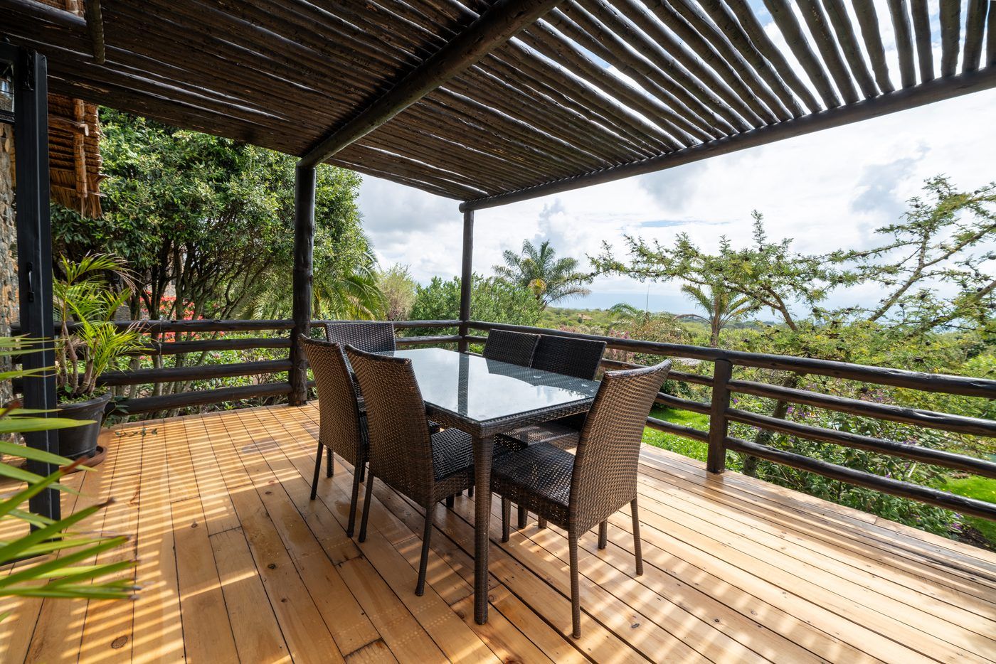 O'Lerai's timber deck under its pole pergola, the glass table and six chairs, the bush running out toward the lake plain.